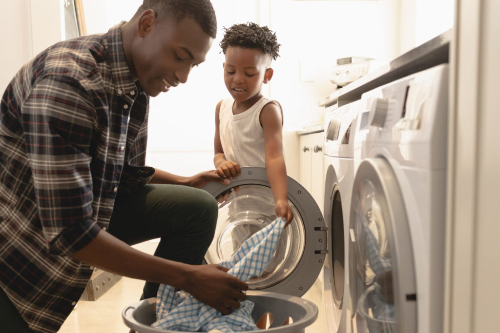 father and son washing clothes in washing machine at home